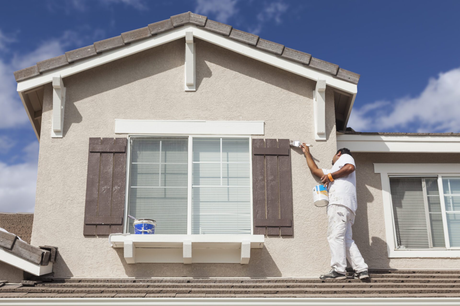 Busy House Painter Painting the Trim And Shutters of A Home. Busy House Painter Painting the Trim And Shutters of A Home.